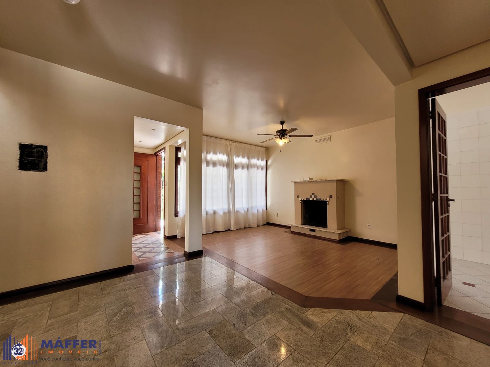 Casa de dois pavimentos com amplo living, lareira, sacada e garagem.
