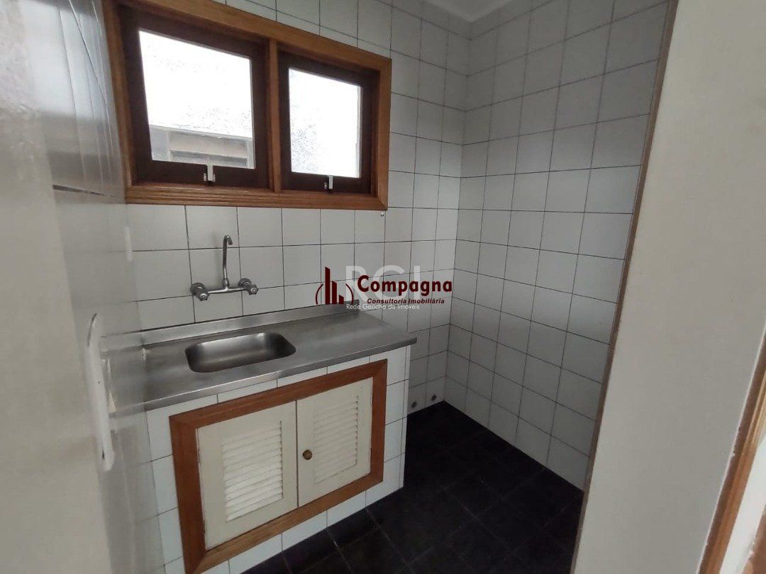 JK no Centro Histórico de Porto Alegre, com 26,01 m², cozinha com pia e armários, banheiro com box, piso com tabuão e orientação solar leste (sol da manhã). — foto 4