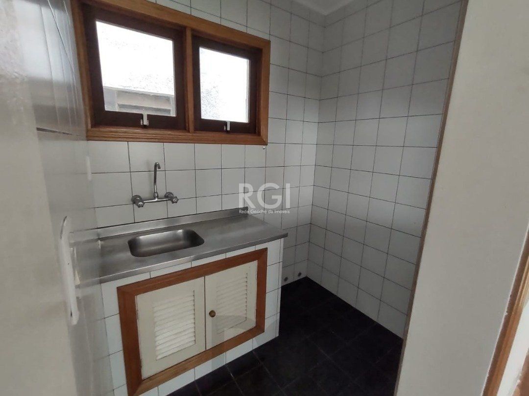 JK no Centro Histórico de Porto Alegre, com 26,01 m², cozinha com pia e armários, banheiro com box, piso com tabuão e orientação solar leste (sol da manhã). — foto 4